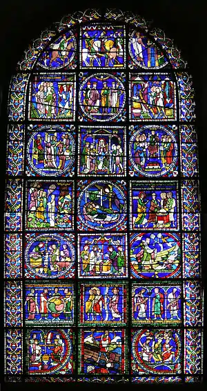 Round-topped window with ancient glass, predominantly blue.