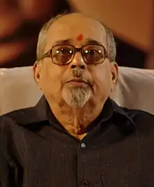 Photograph of an old man wearing black glasses.